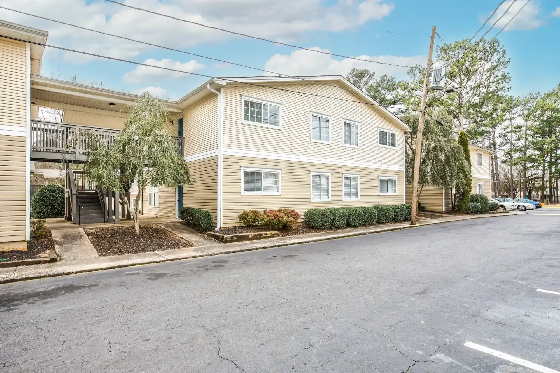 A building with a lot of windows is sitting on the side of the road next to a parking lot.