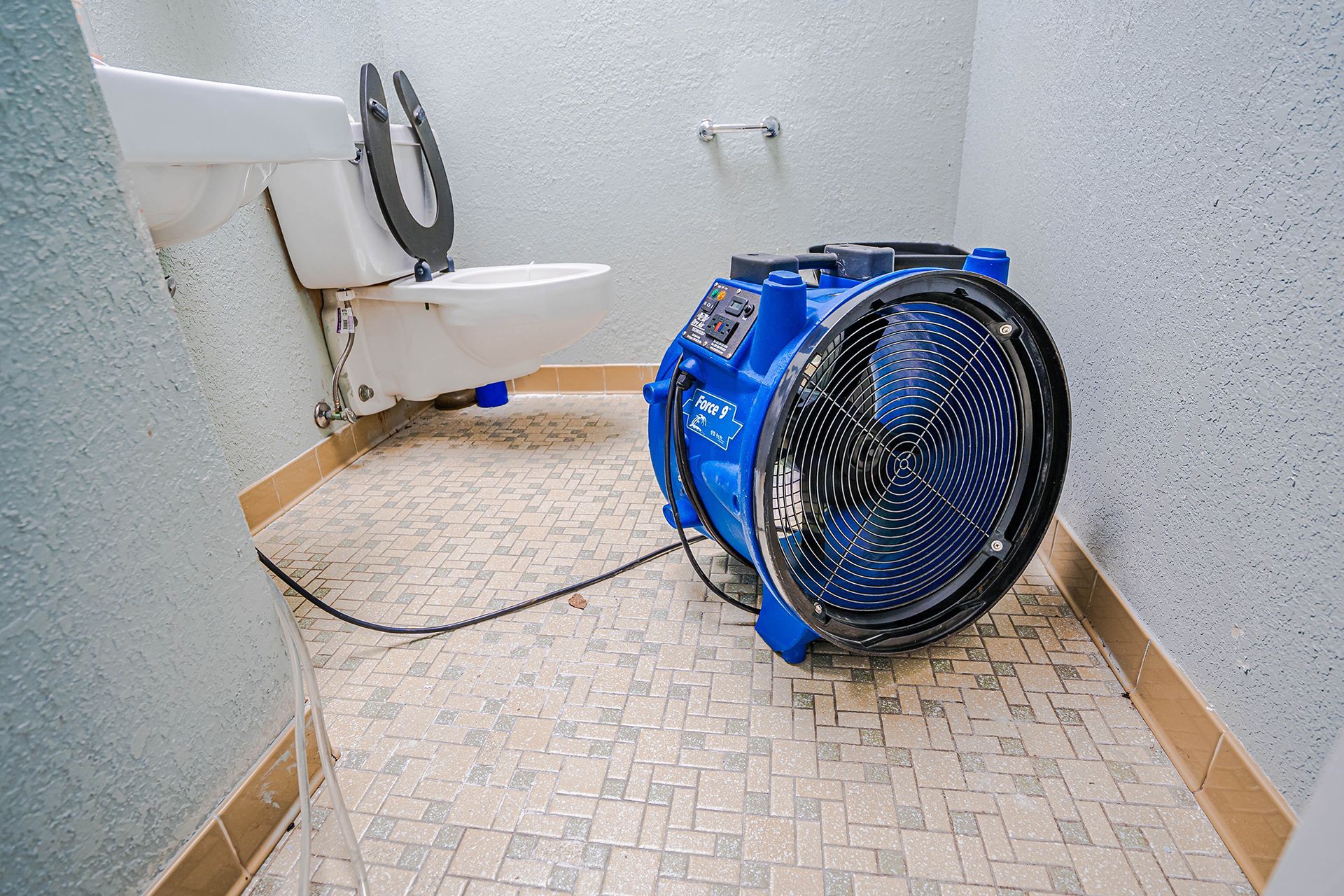 A bathroom with a large water restoration fan.