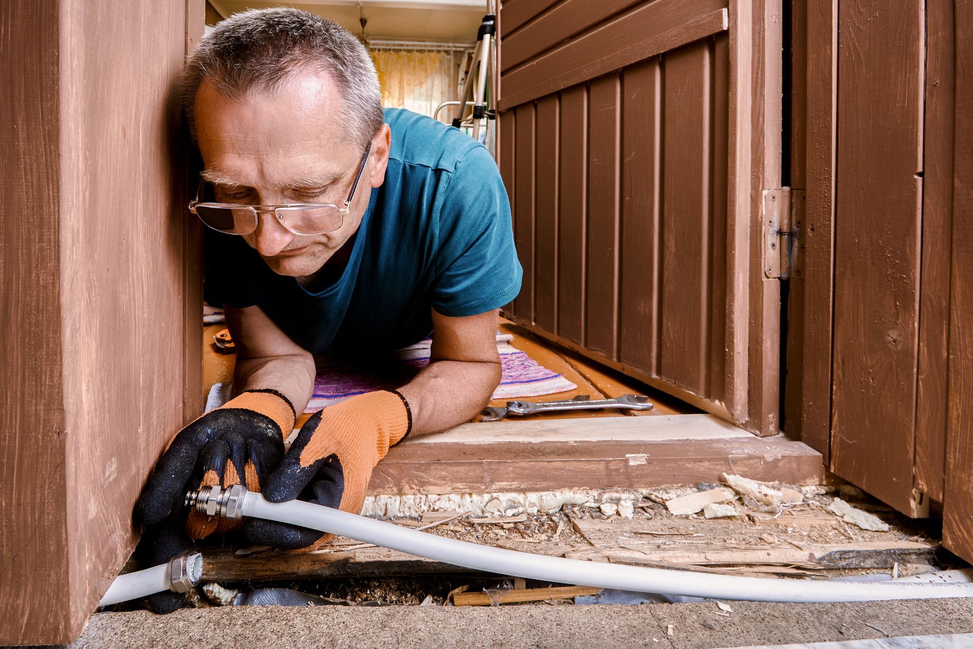 A plumber connects split multilayer tubing using compression coupling to restore a damaged water pipeline.