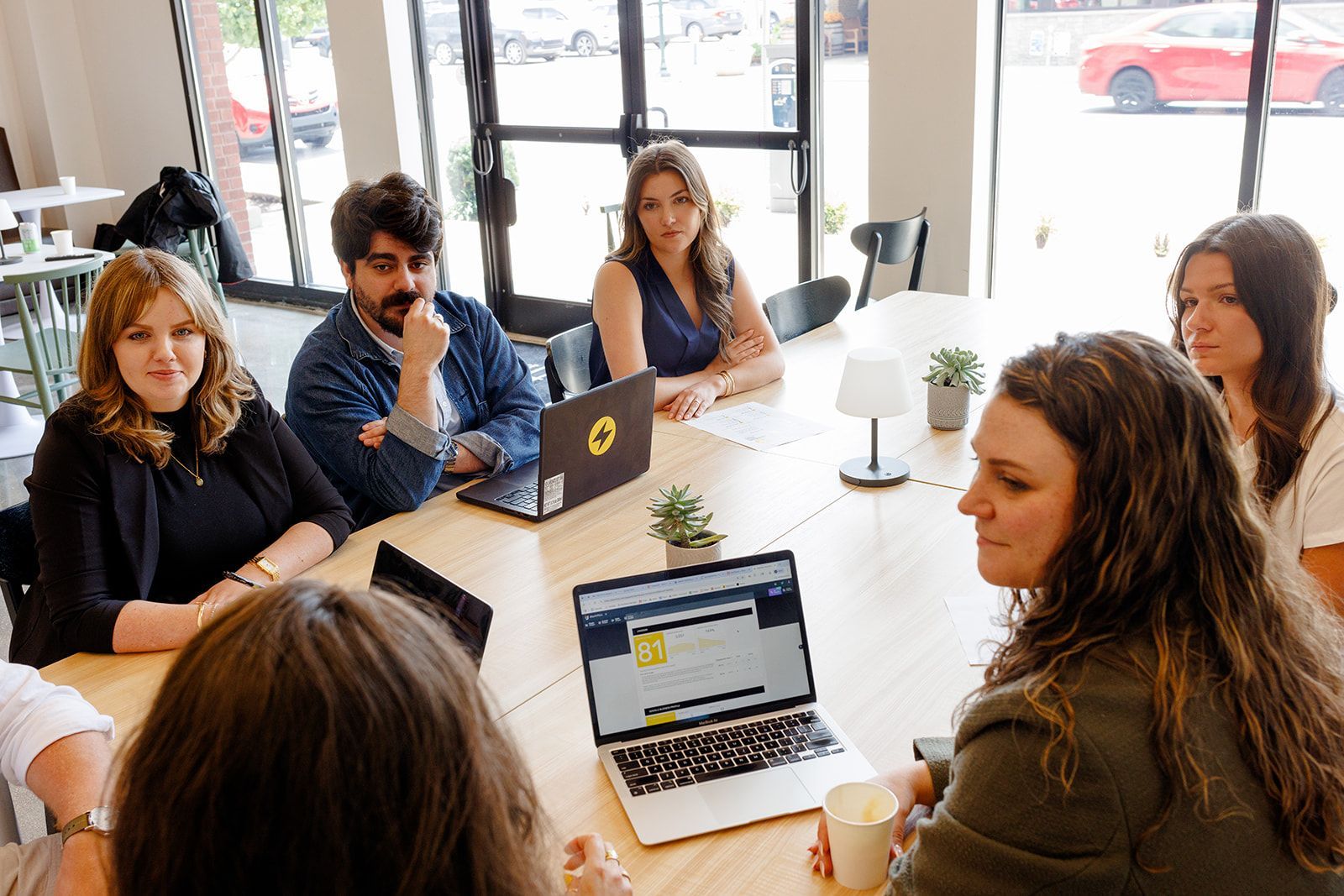 A group of people are sitting around a table with laptops.