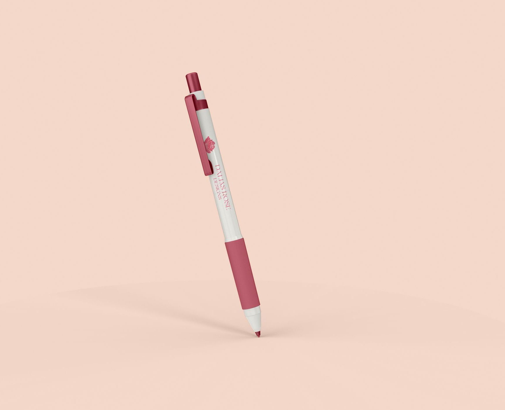 A pink and white pen is sitting on a pink surface.