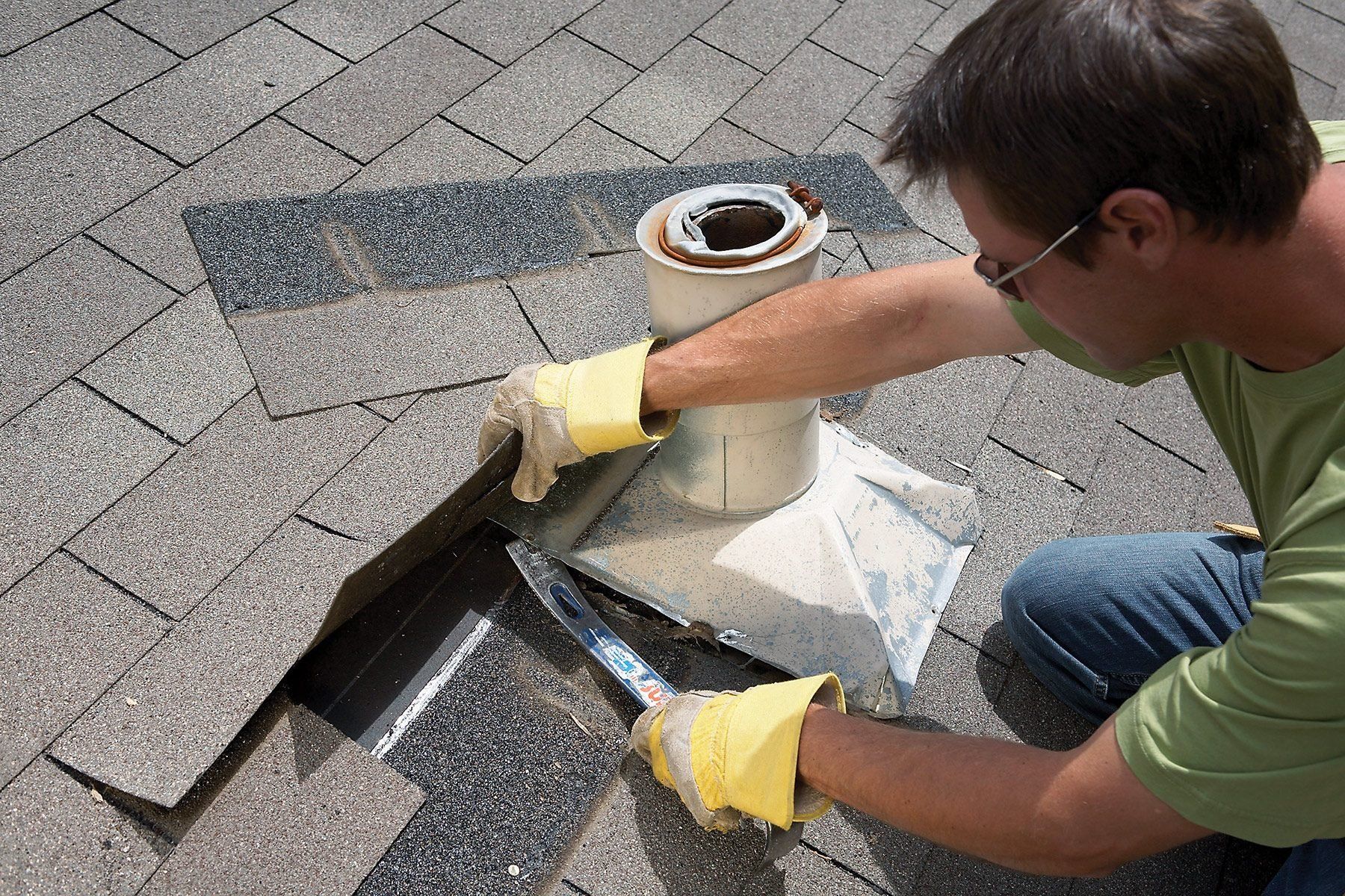 A man is kneeling down on the ground working on a roof.