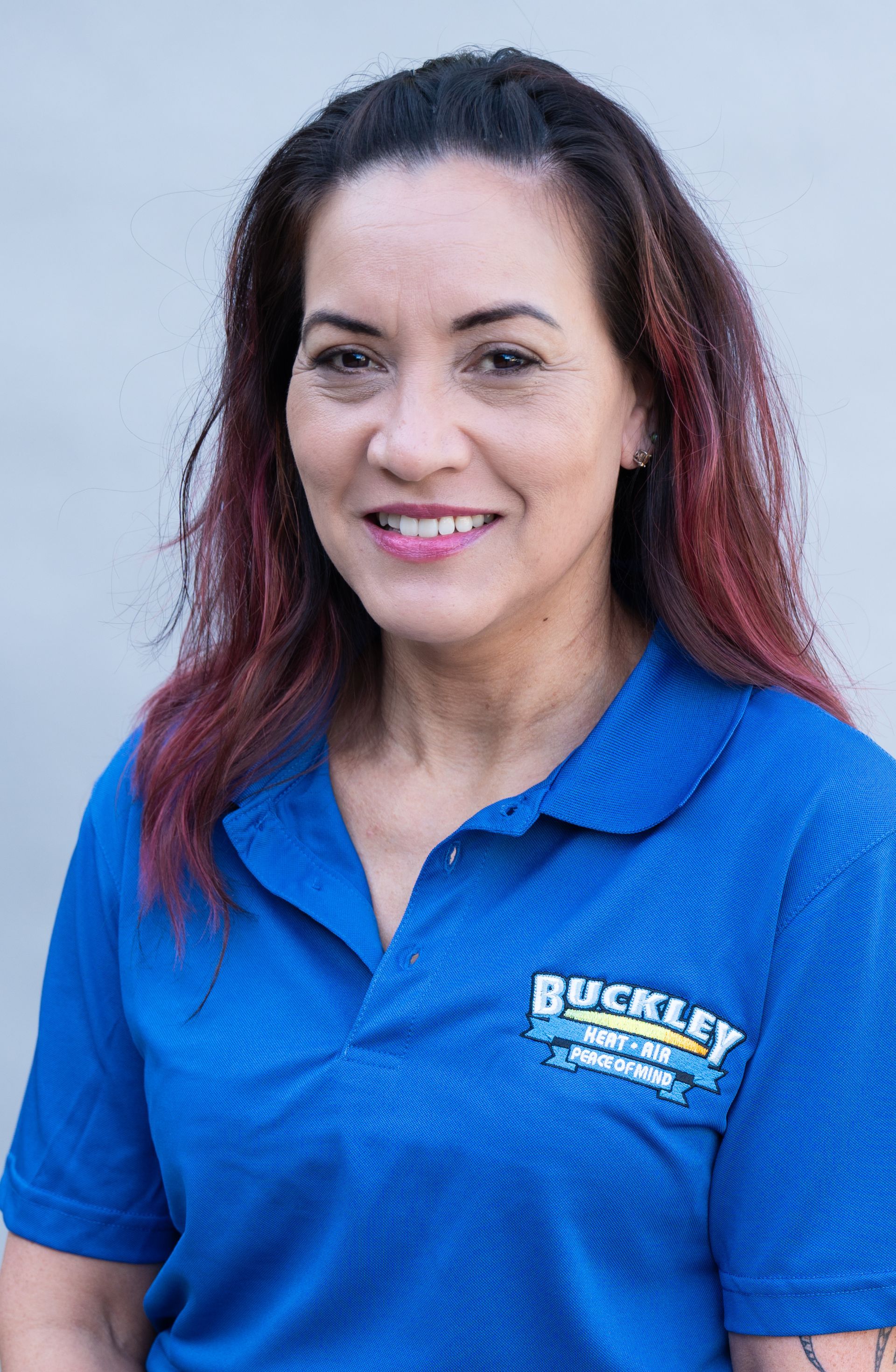 A woman wearing a blue polo shirt is smiling for the camera.