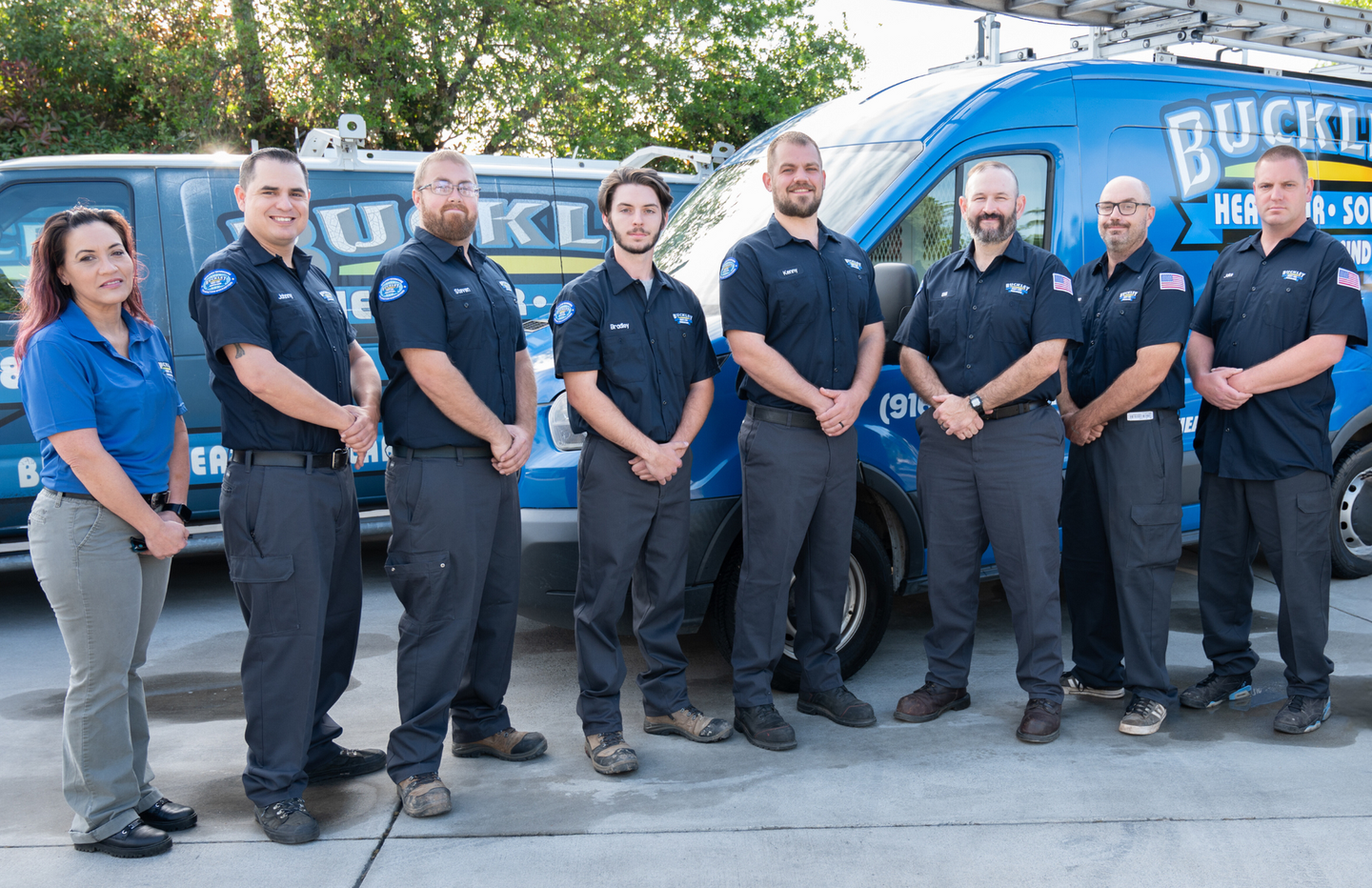 The Buckley team is standing next to each other in front of a van.