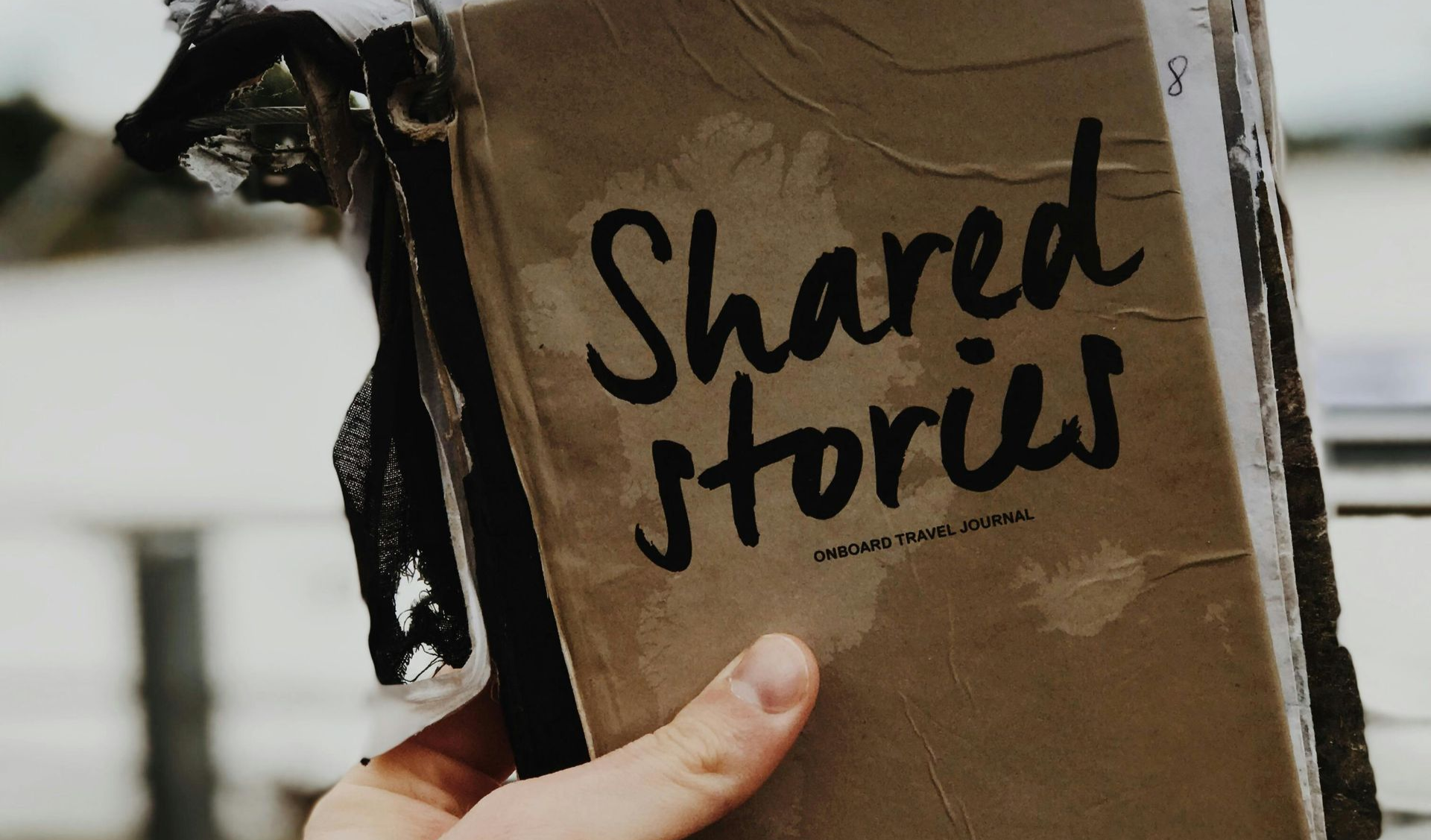 hand holding a tattered journal titled Shared Stories
