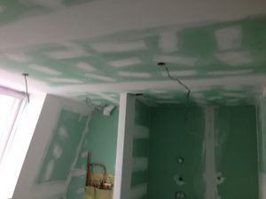 Een kamer met groene muren en een wit plafond wordt verbouwd.