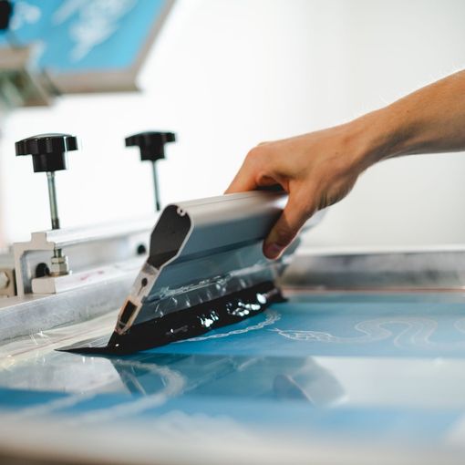 a person is using a screen printing machine to print a picture on a piece of paper .