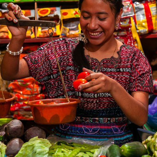 a woman is standing in front of a table full of vegetables .