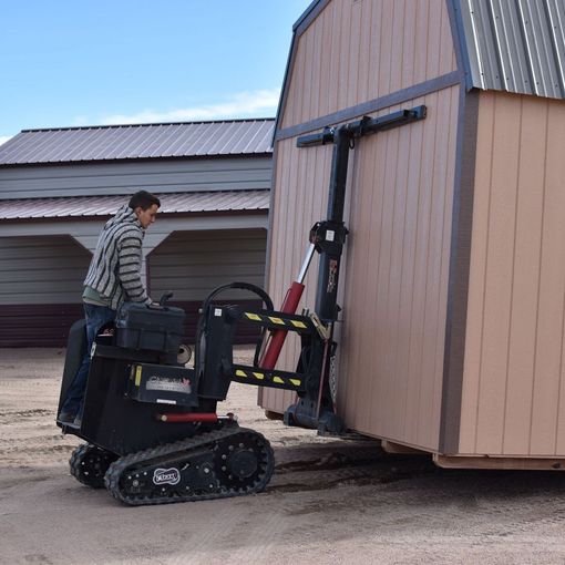 a man is pushing a shed with a forklift .