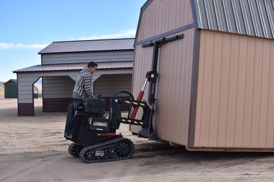 a man is pushing a shed with a forklift .