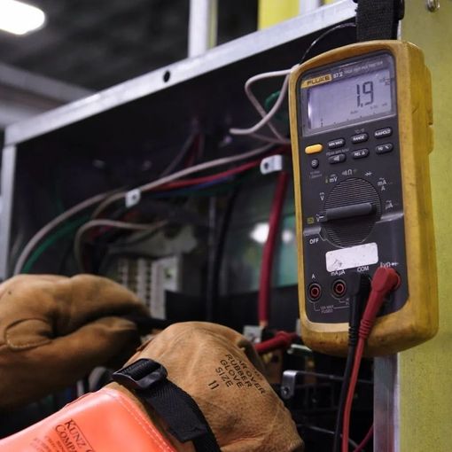 a man is working on a machine with a multimeter .