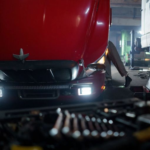 a man is working on a semi-truck in a garage .