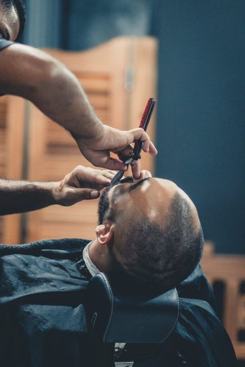 a man is getting his beard shaved by a barber .
