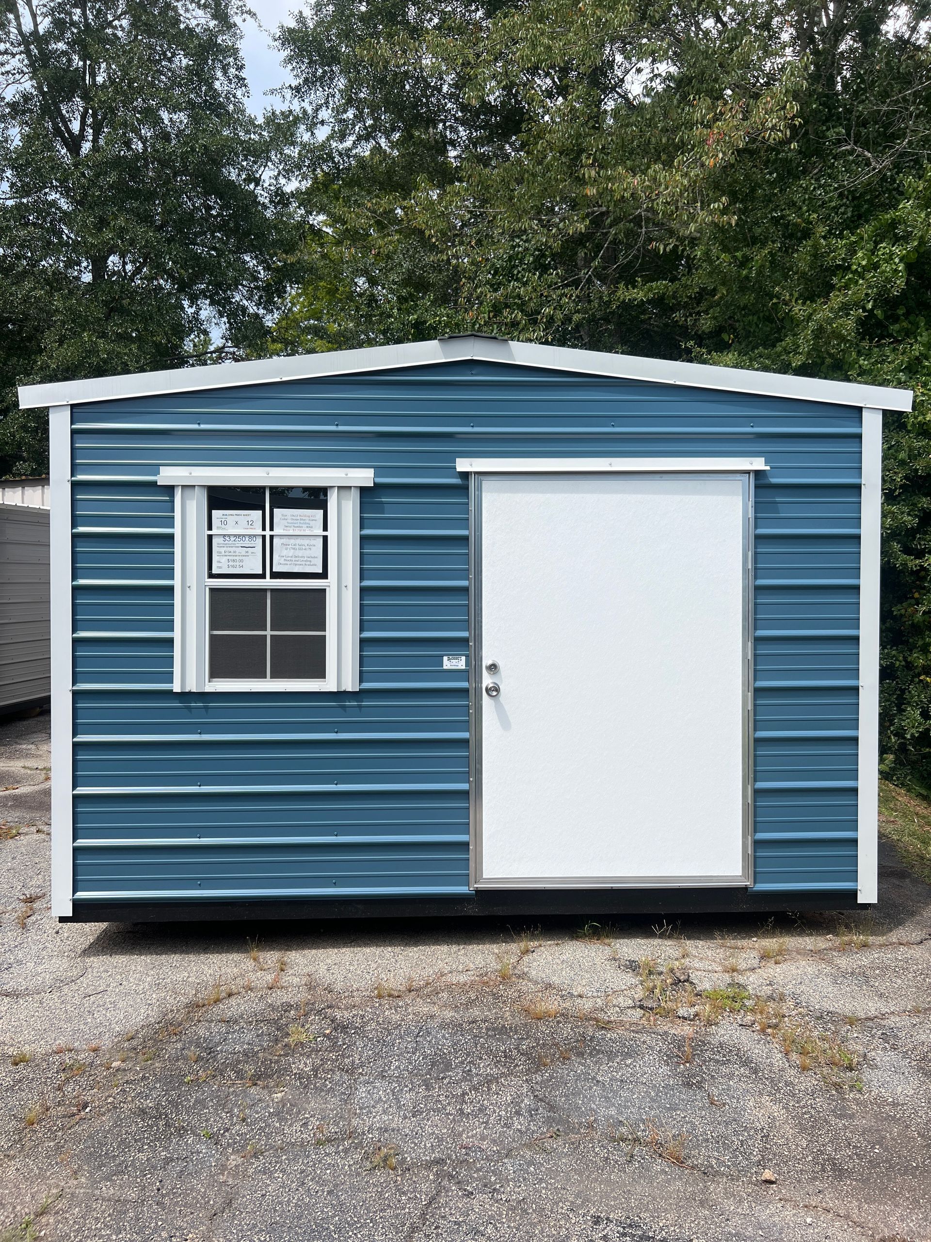 Blue and white metal shed with door and window, outdoors.