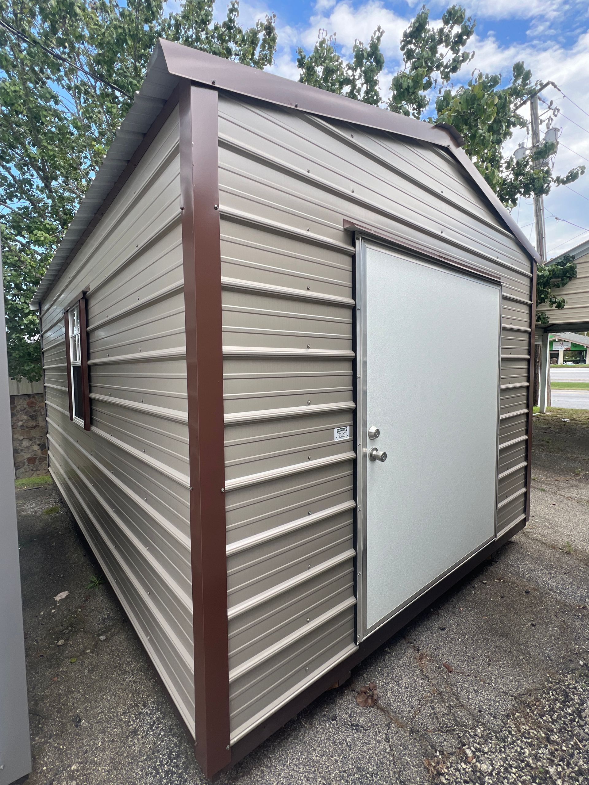 Tan metal shed with brown trim, a sliding door, and a small window.