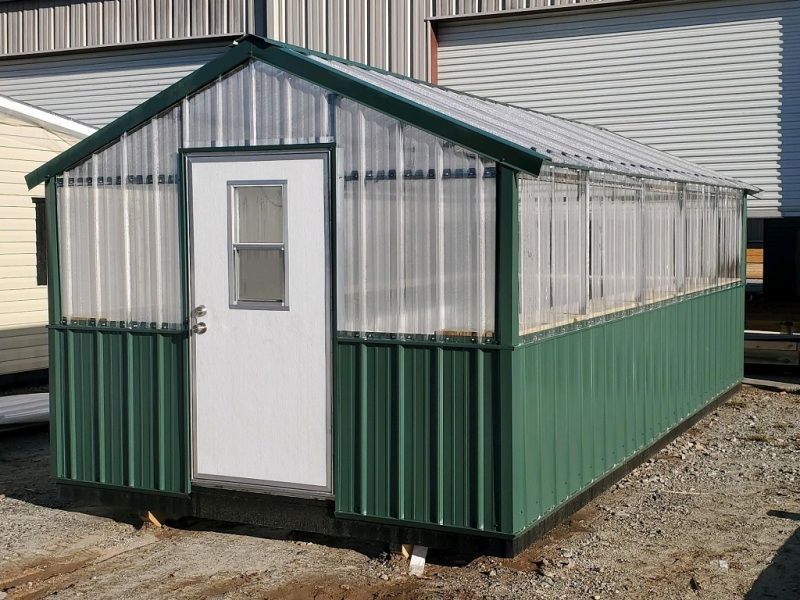 Greenhouse with corrugated metal siding, clear roof panels, and a white door.