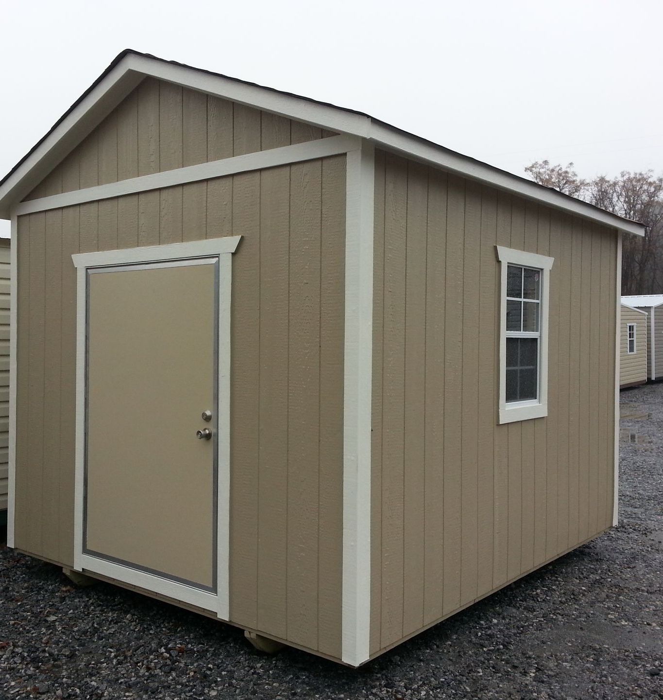A tan shed with a white trim and a window