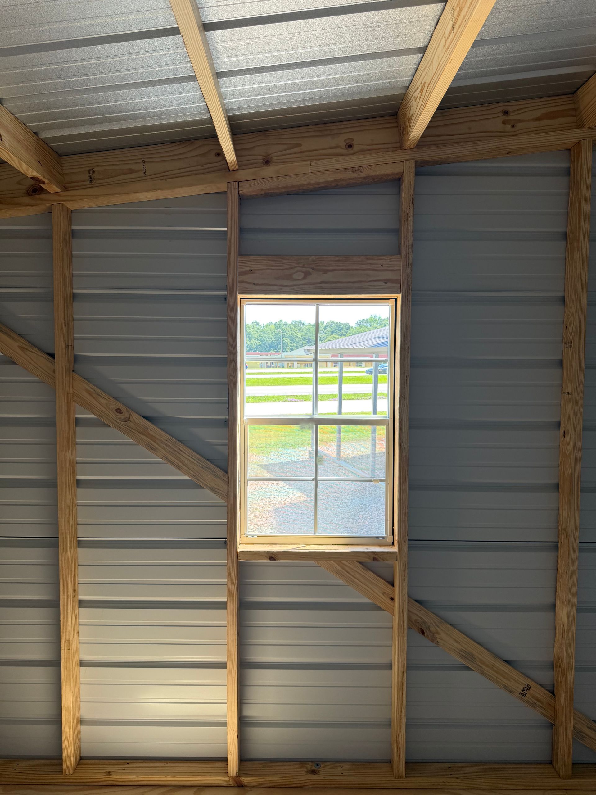 Interior of a small shed with corrugated metal walls and a centered window showing a field outside.