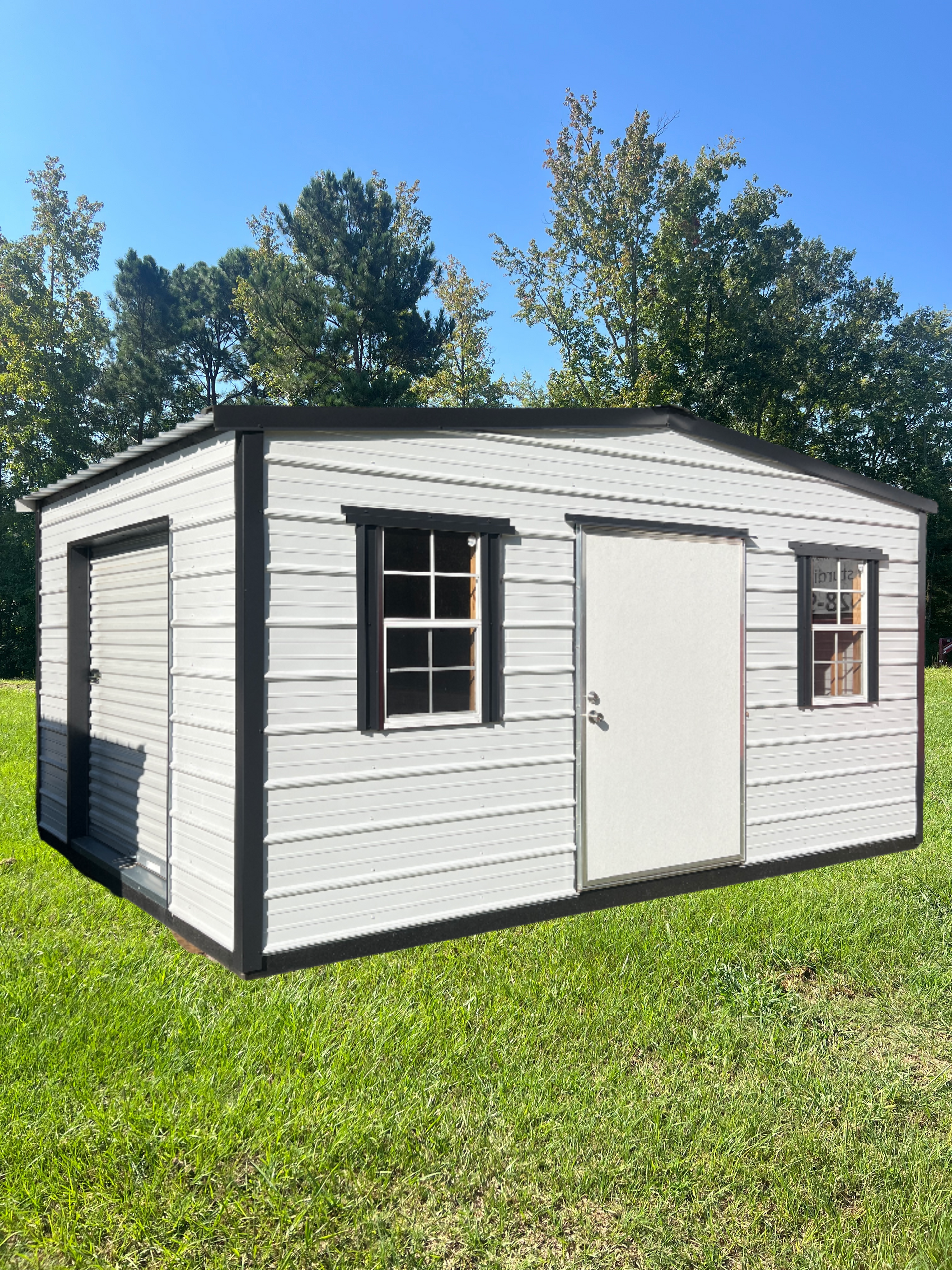 Gray shed with dark brown trim, windows, and door on a grassy lawn under a blue sky.