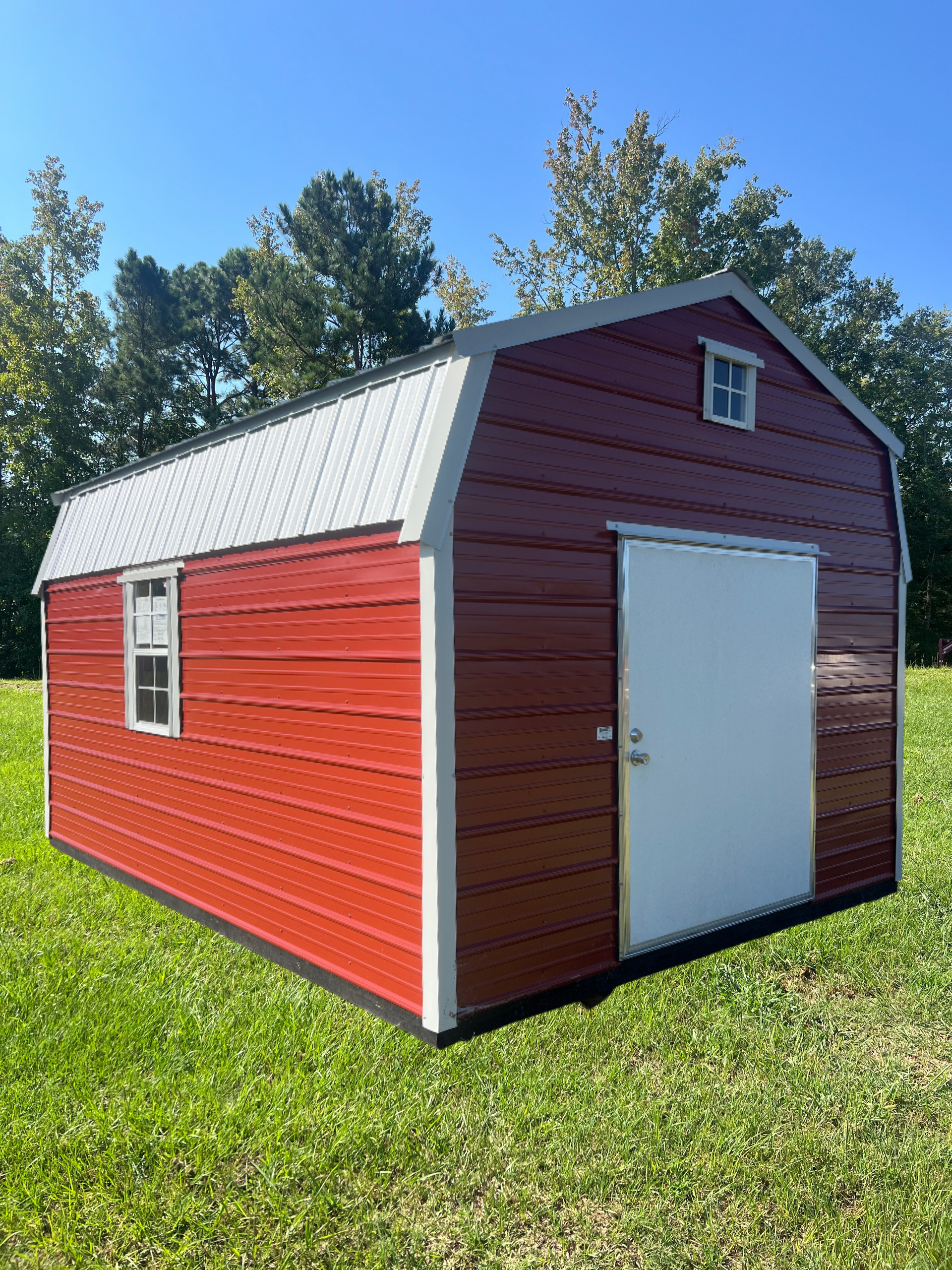 Red barn-style shed with a white door and windows, set on green grass under a blue sky.