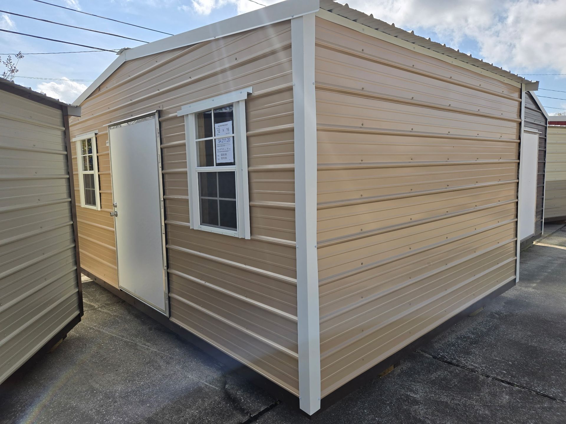 Tan metal storage shed with a door and window.