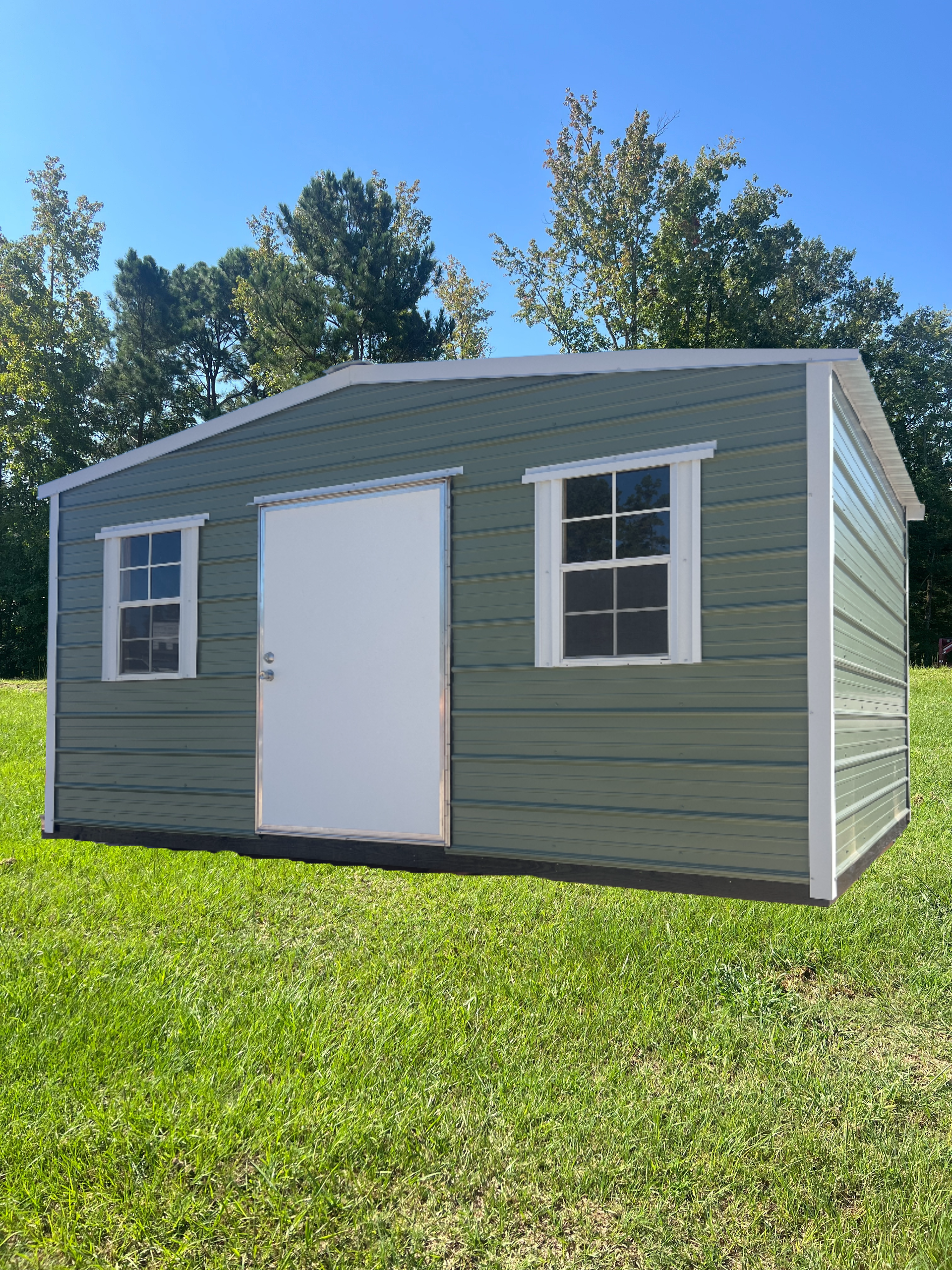 Green shed with white trim and door, two windows, set in grass.
