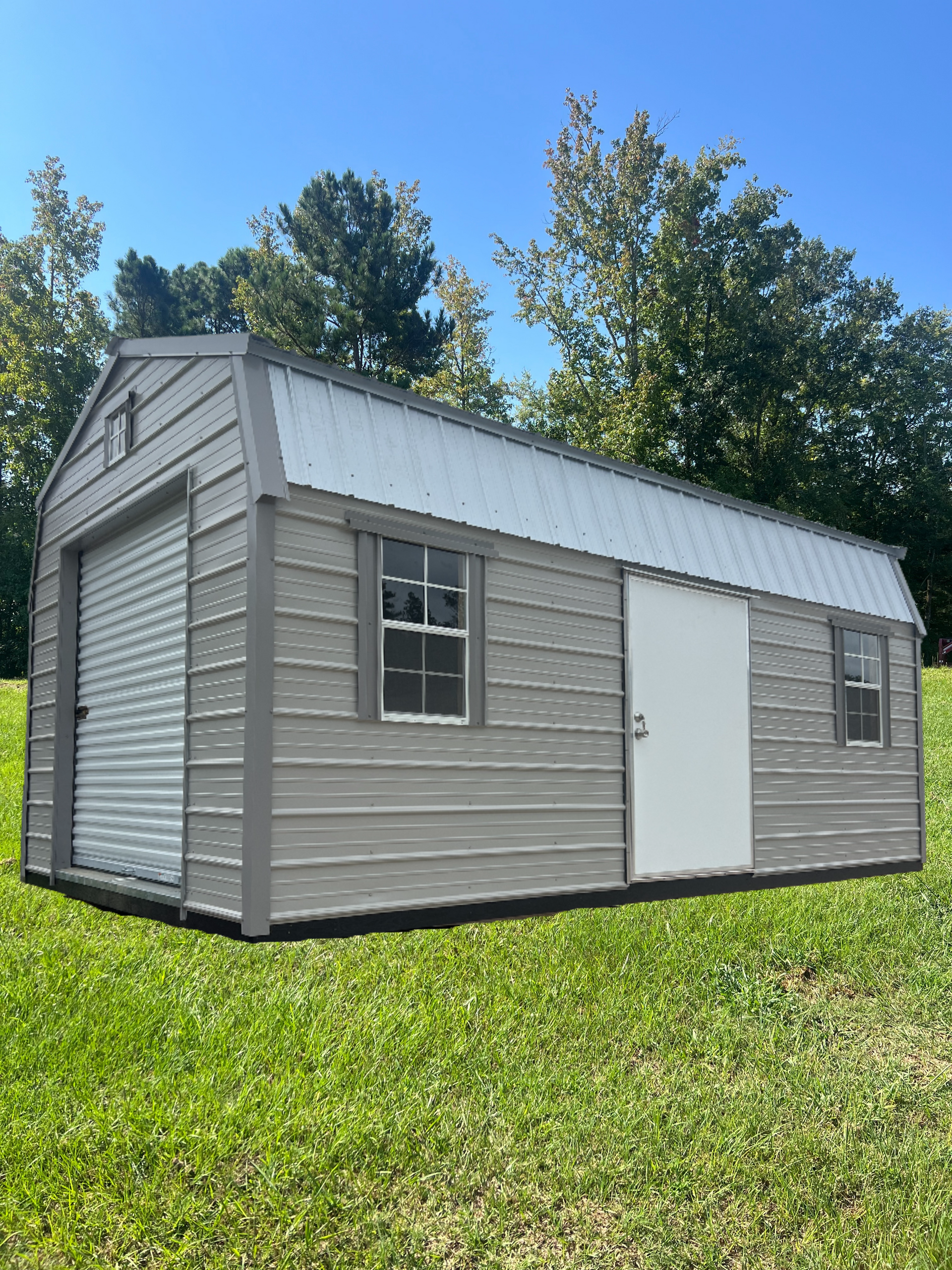 Tan and brown barn-style shed with silver roof, white door, and windows on gravel.