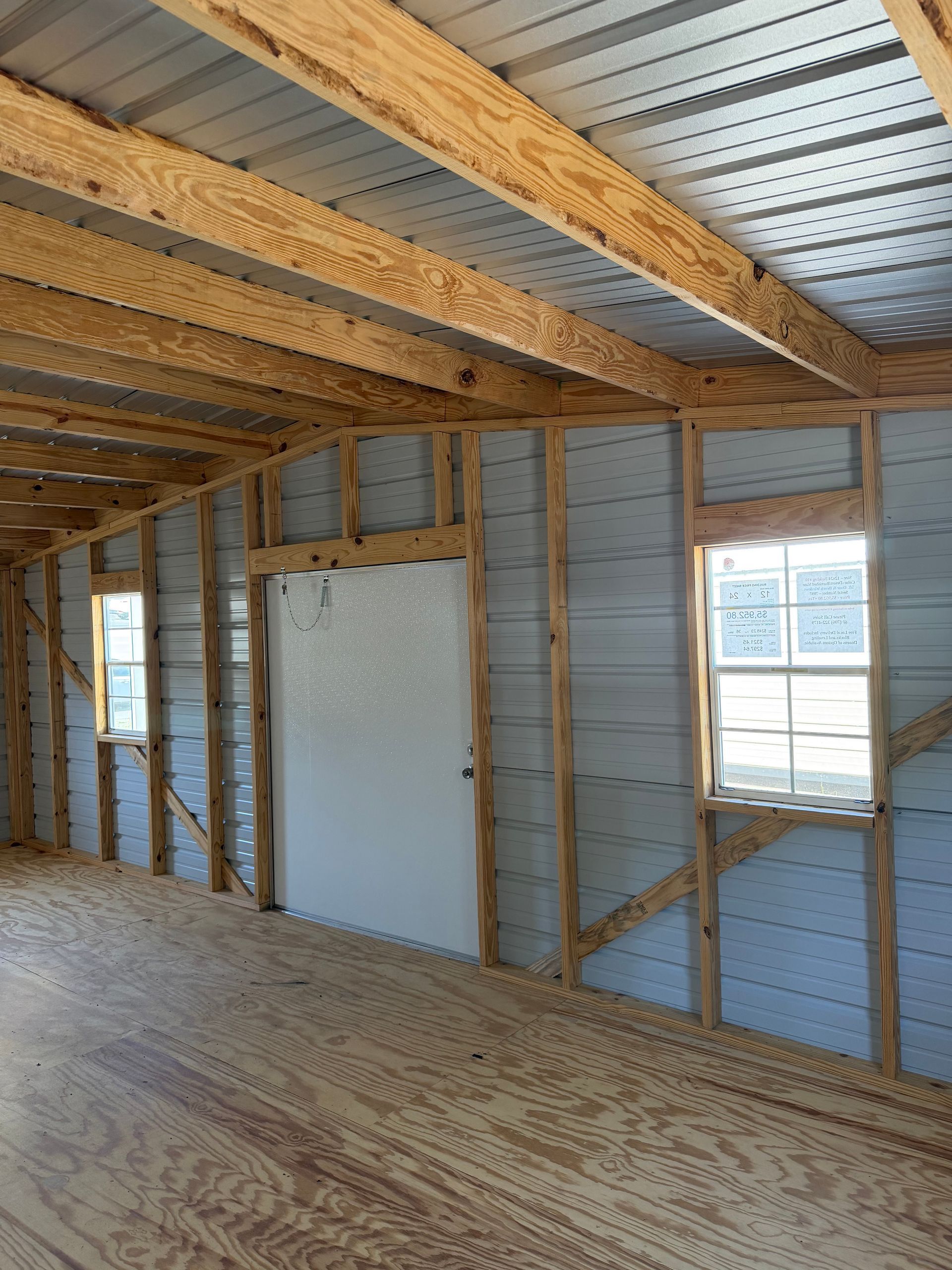 Interior of a house under construction with exposed wall studs, insulation, and a white door and window.