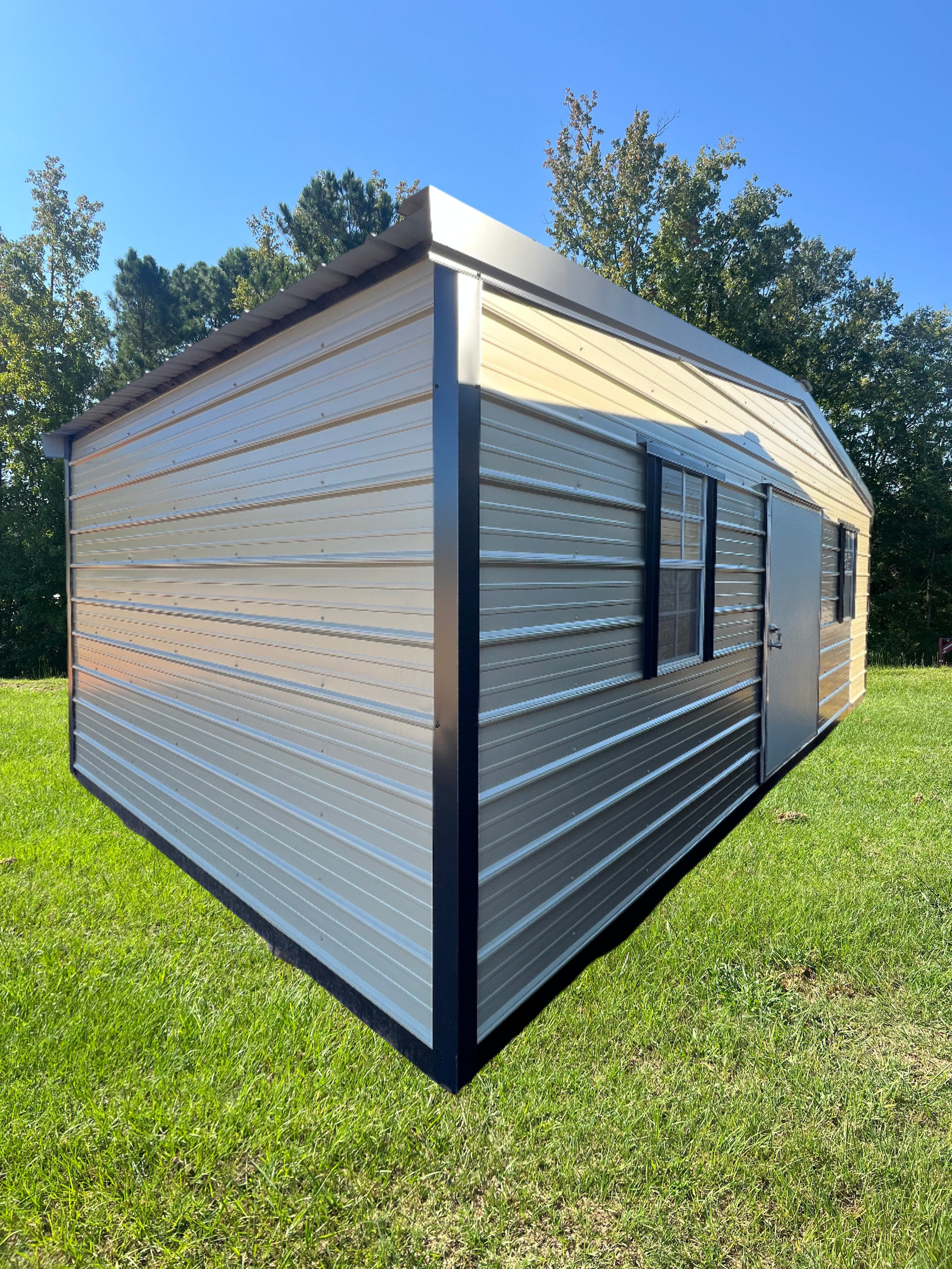 Metal storage shed with a sloped roof, black trim, and a window and door on a grassy lawn.