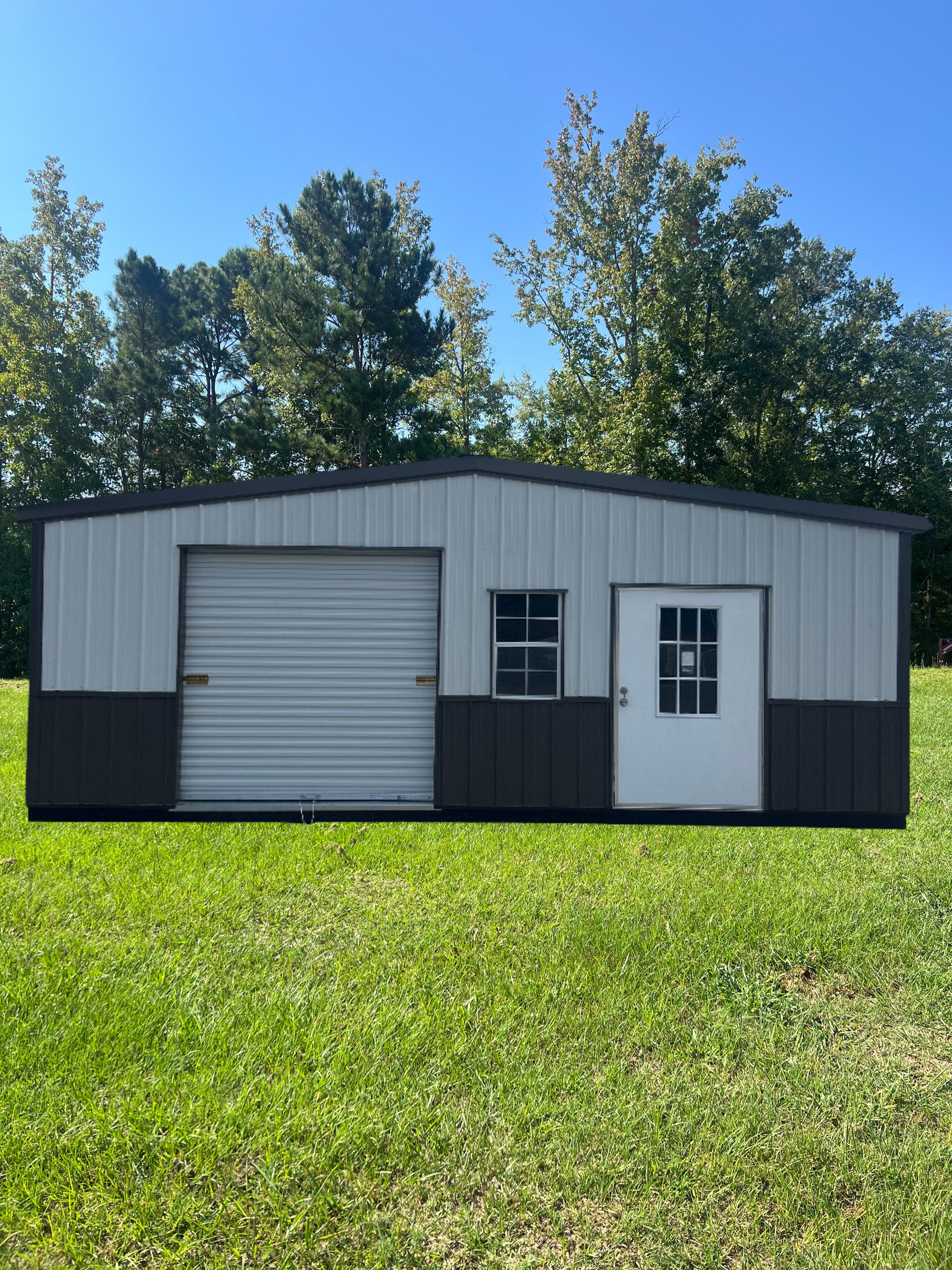Metal storage building with gray and dark gray panels, garage door, white door, and window in a grassy field.