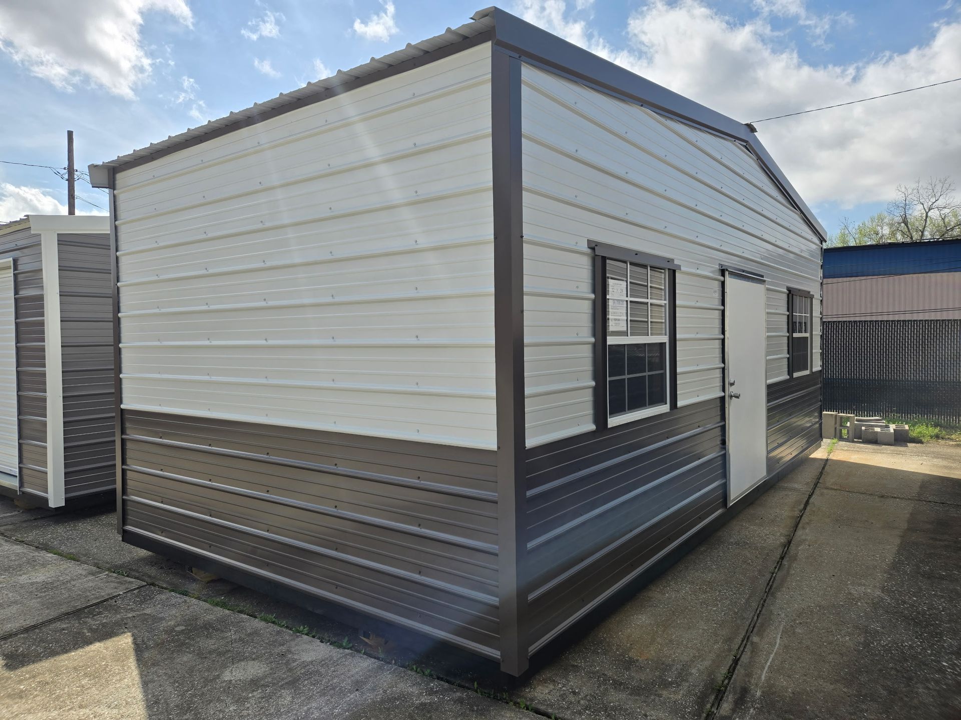 Metal storage shed with brown and white panels, door, window. Outdoor setting.