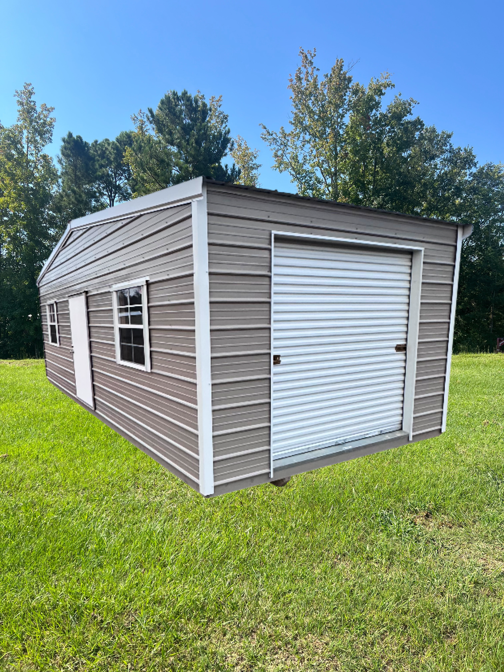 Gray shed with white trim, roll-up door, window, and door, set in a grassy yard.