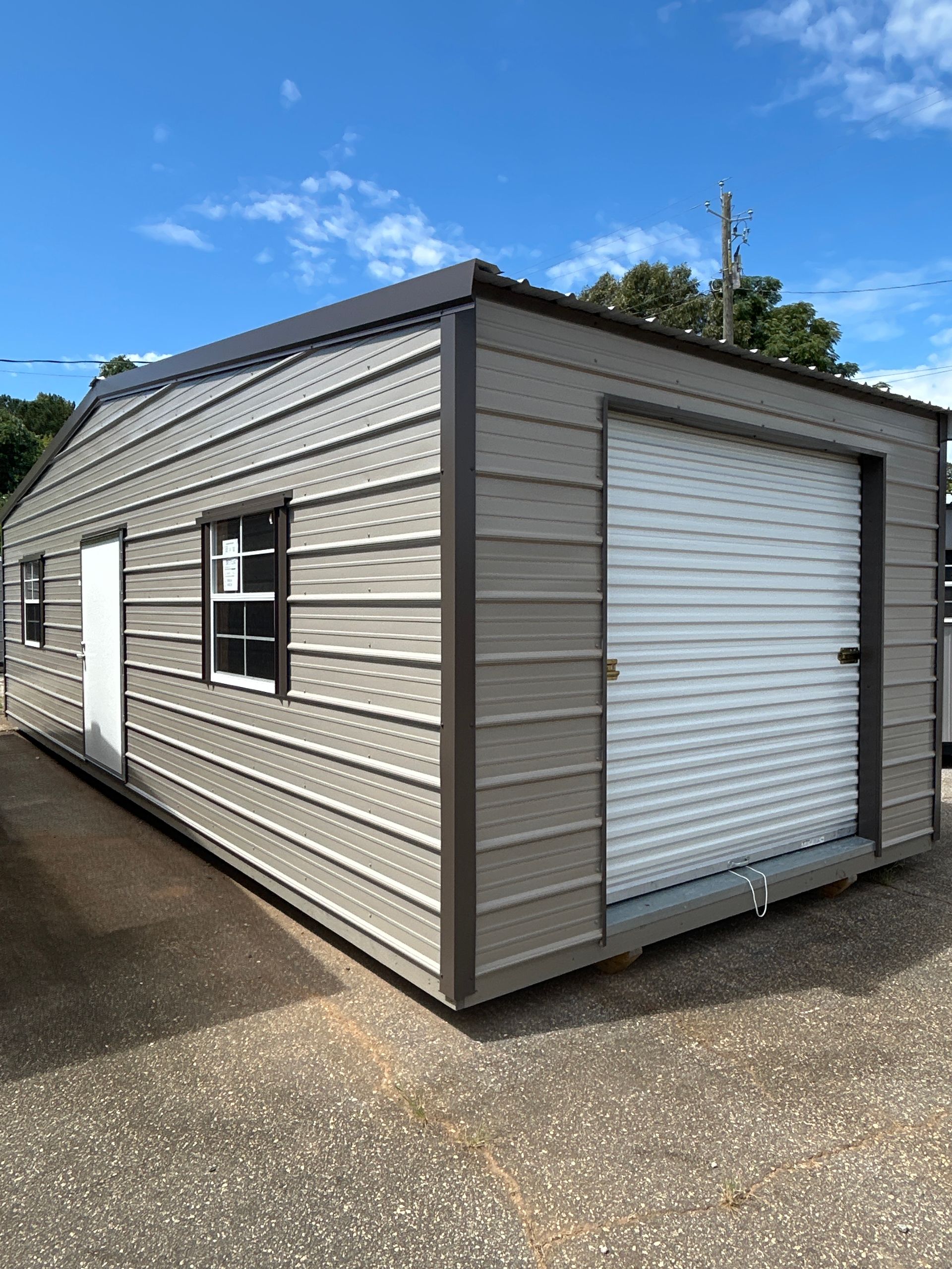 Metal garage with a roll-up door, window, and a side door on a sunny day.