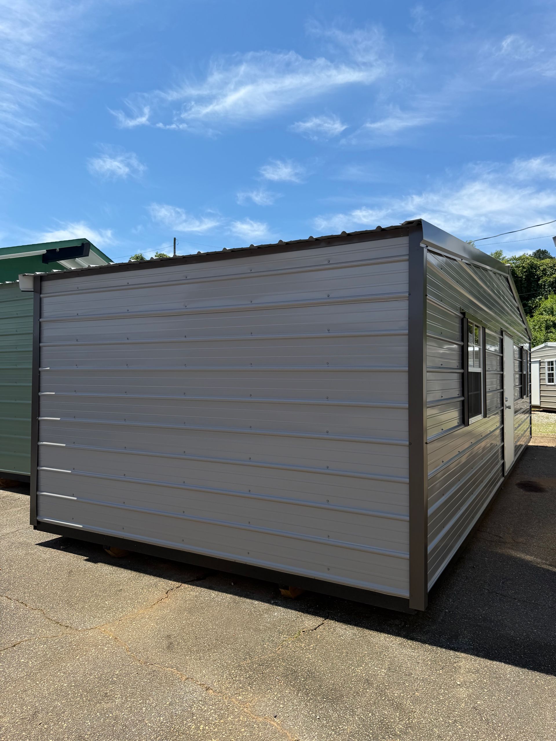 Portable modular building with white siding and a dark frame under a blue sky