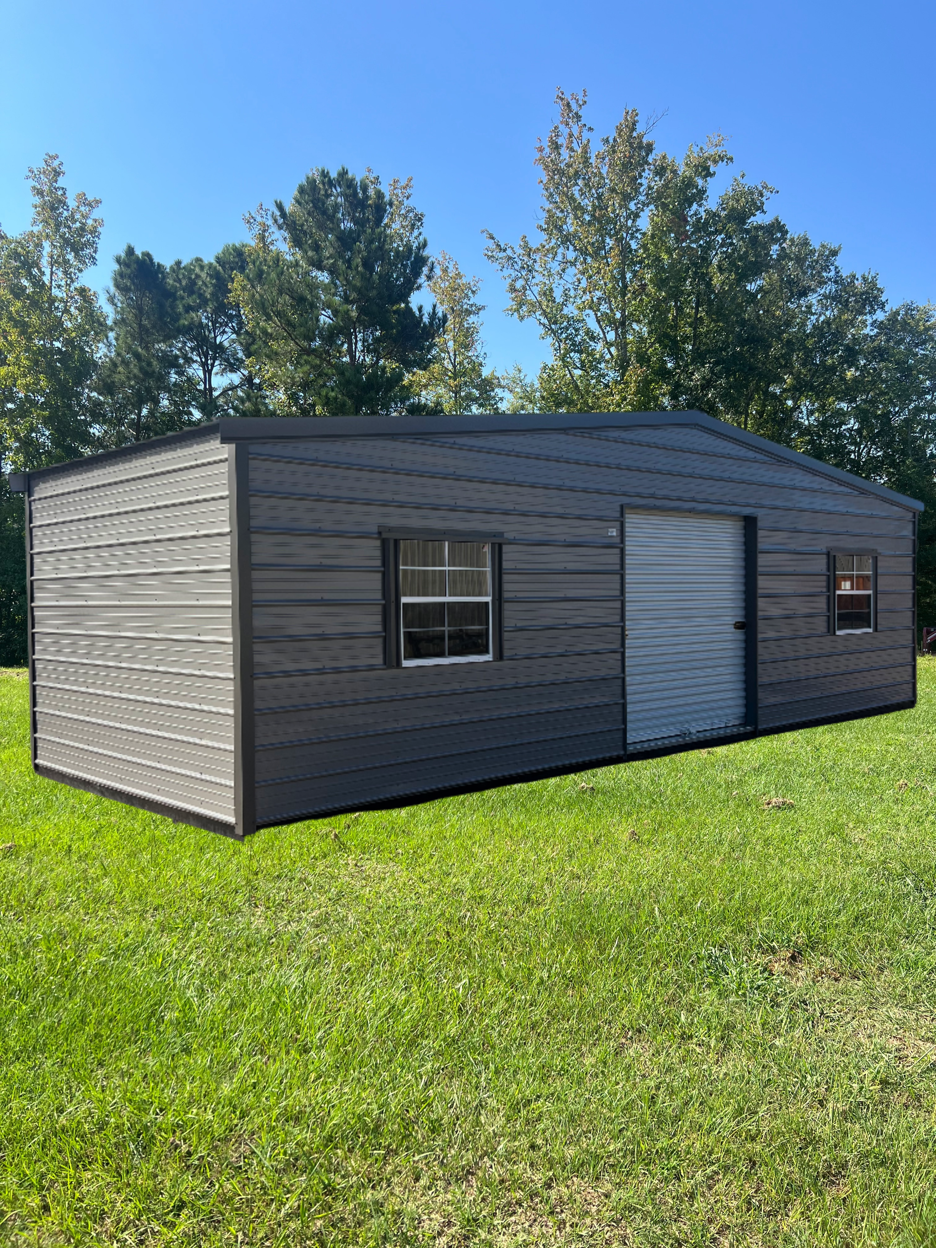 Gray metal shed with a roll-up door, windows, and corrugated siding on a grassy lawn.