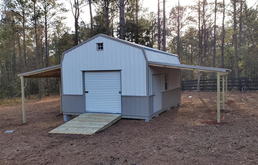 A shed with a ramp and a canopy in the middle of a field.