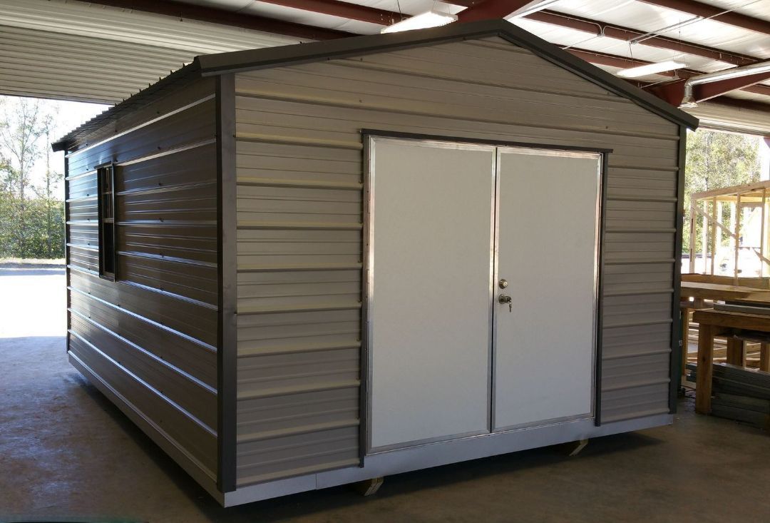 A metal shed with two white doors is sitting inside of a building.