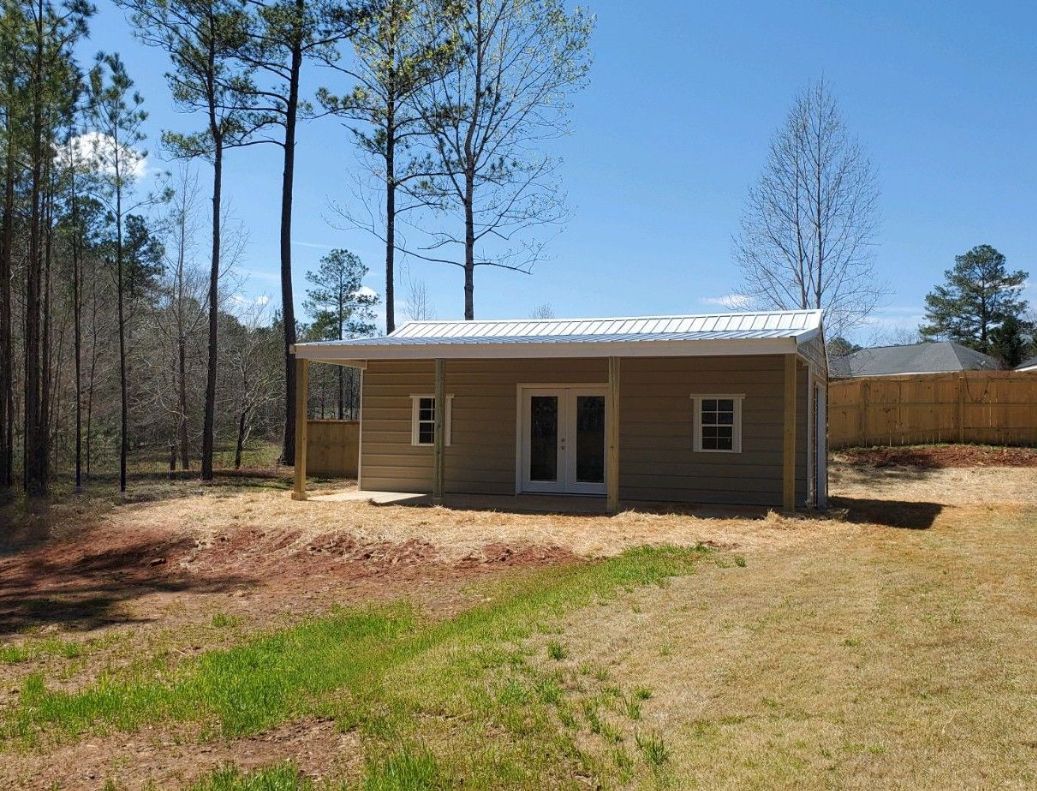 A small house is being built in the middle of a grassy field.