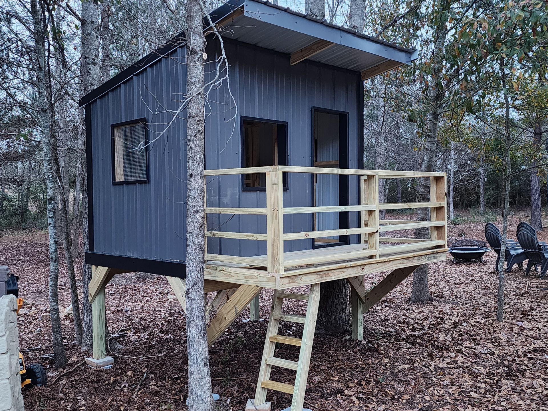 A small house on stilts in the middle of a forest.