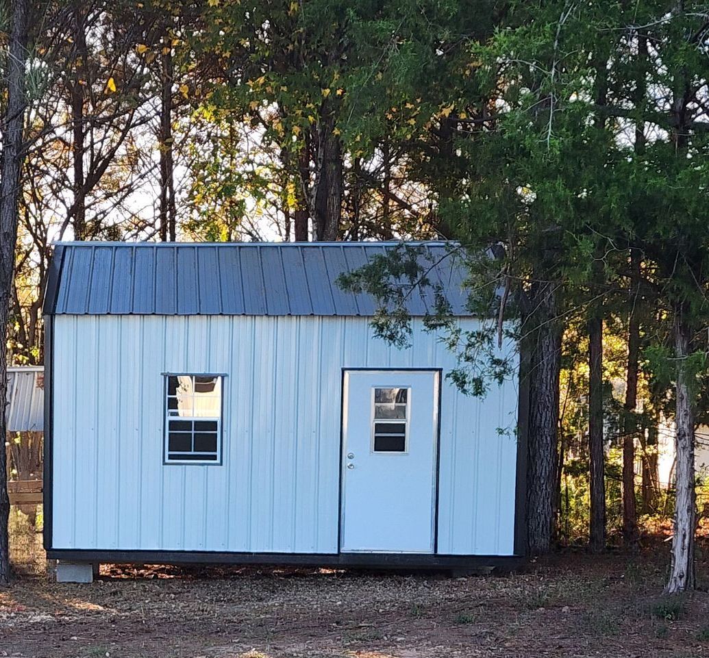A white chicken coop is sitting in the middle of a lush green field.
