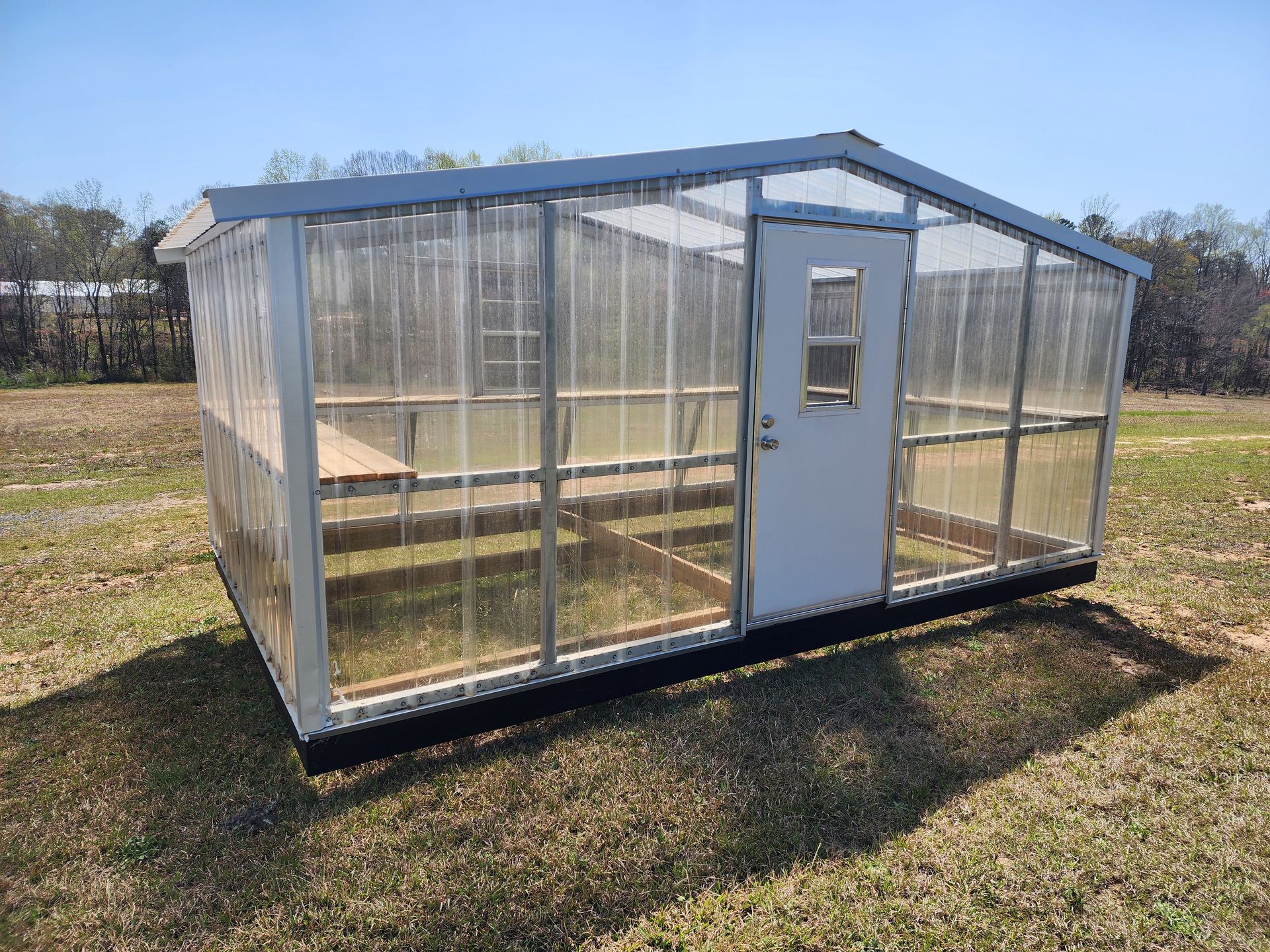 A greenhouse is sitting in the middle of a grassy field.