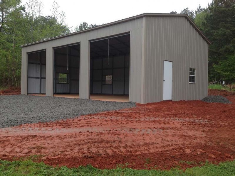 A large building with a white door is sitting in the middle of a dirt field