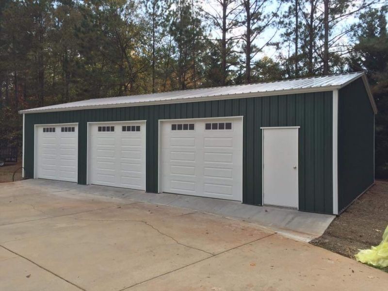 A green garage with four white garage doors and a white door