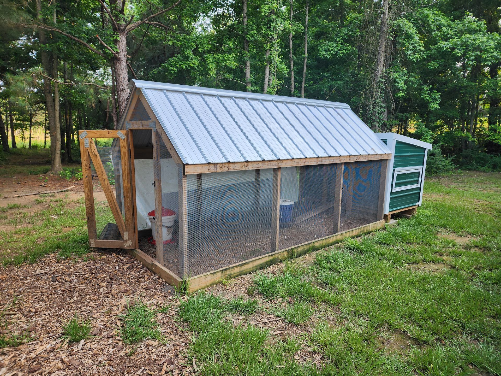 A chicken coop is sitting in the middle of a grassy field.