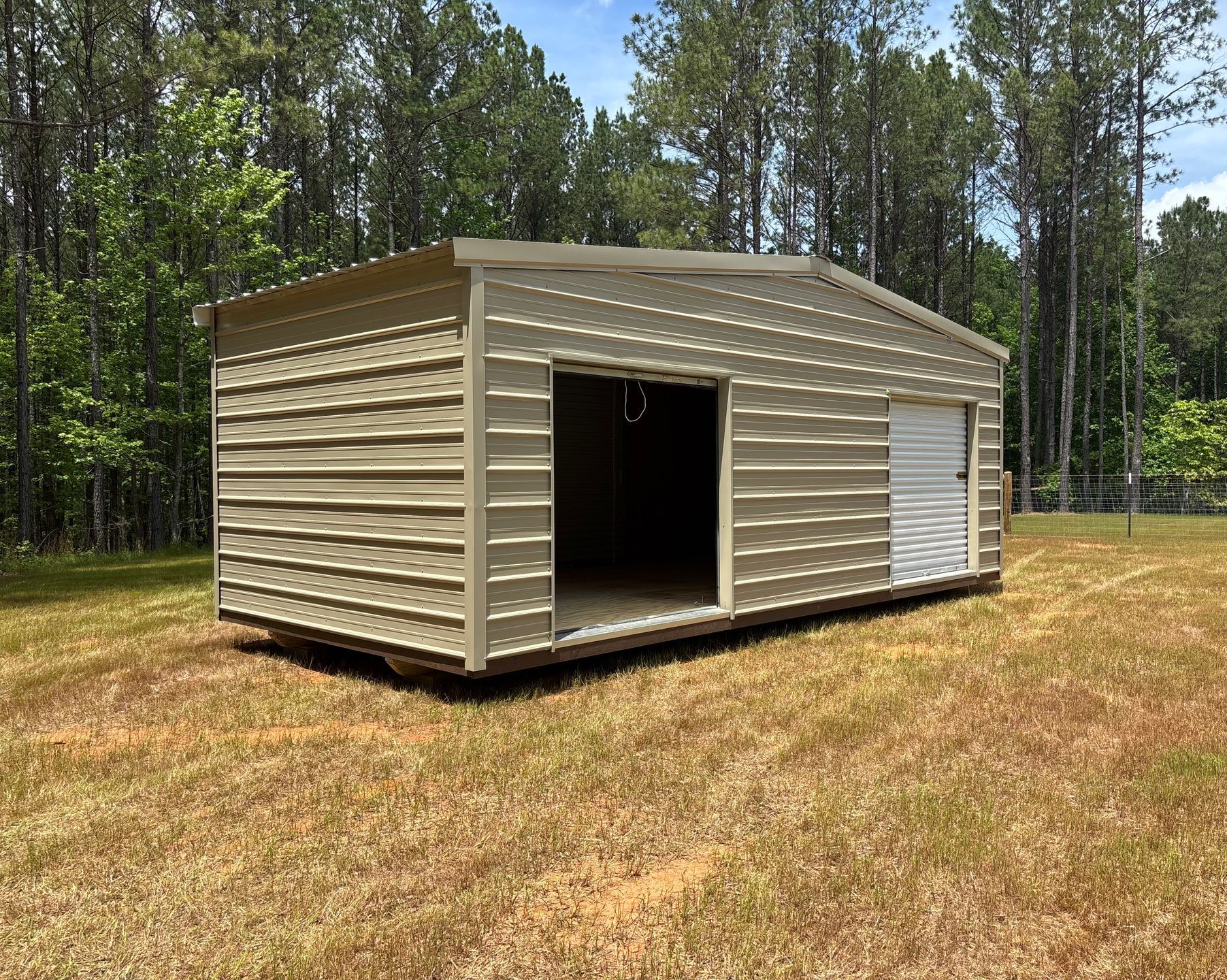 A metal building is sitting in the middle of a grassy field.