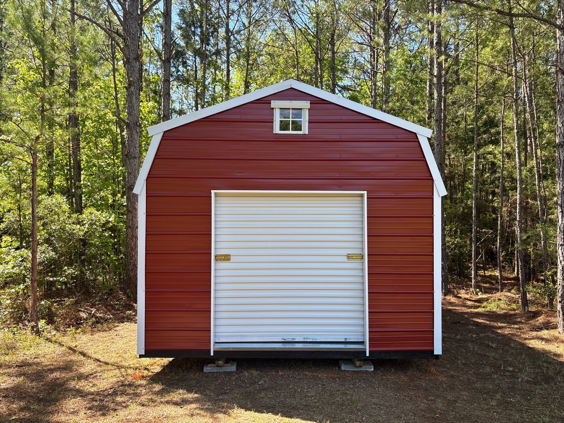 A red barn with a white door is sitting on a dirt field