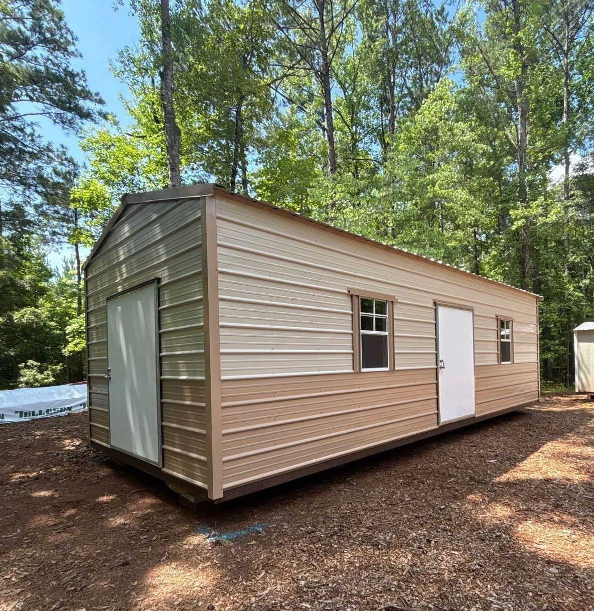 A small shed is sitting in the middle of a dirt field.