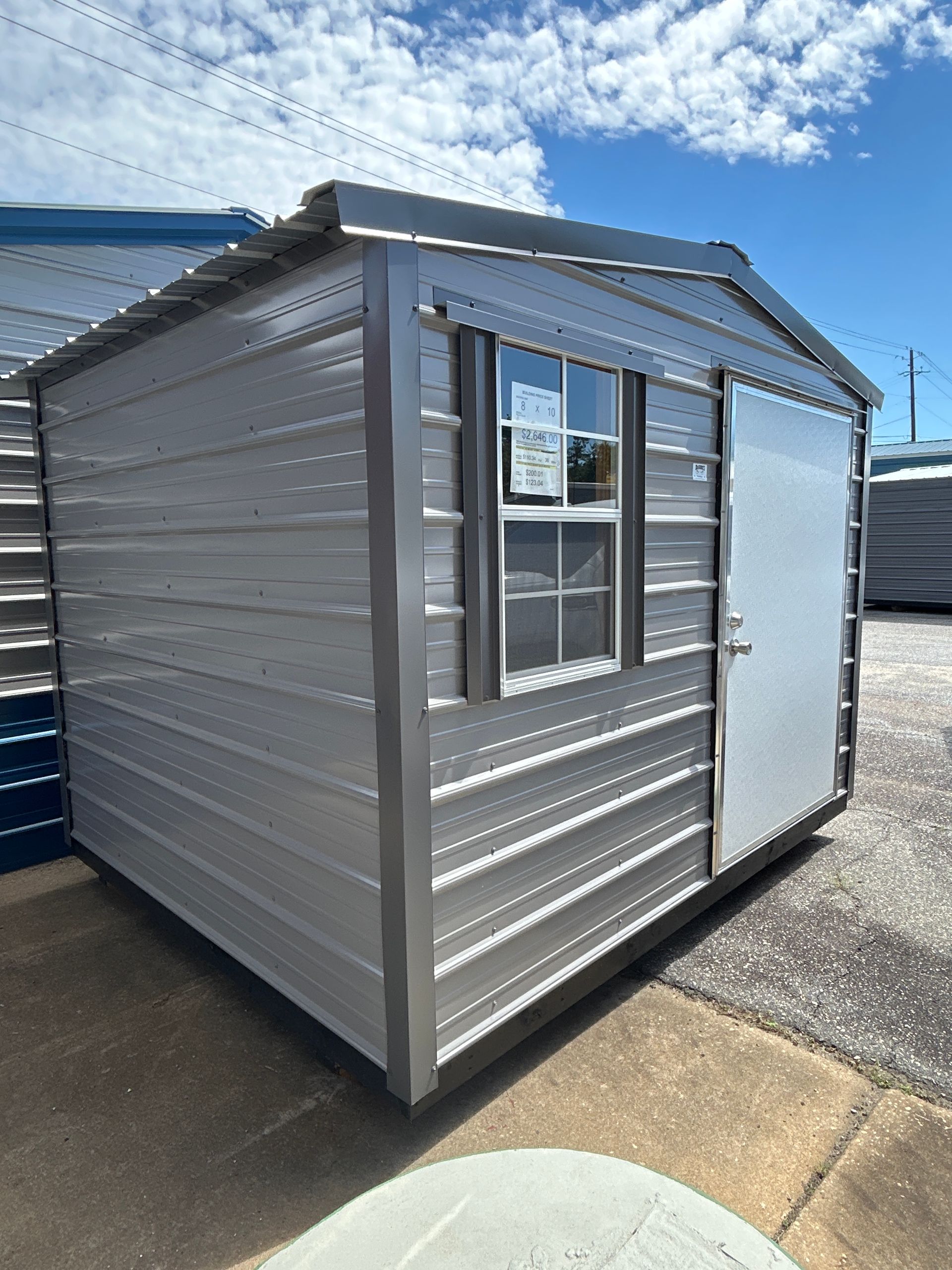 Metal shed with window and door on a brick surface.