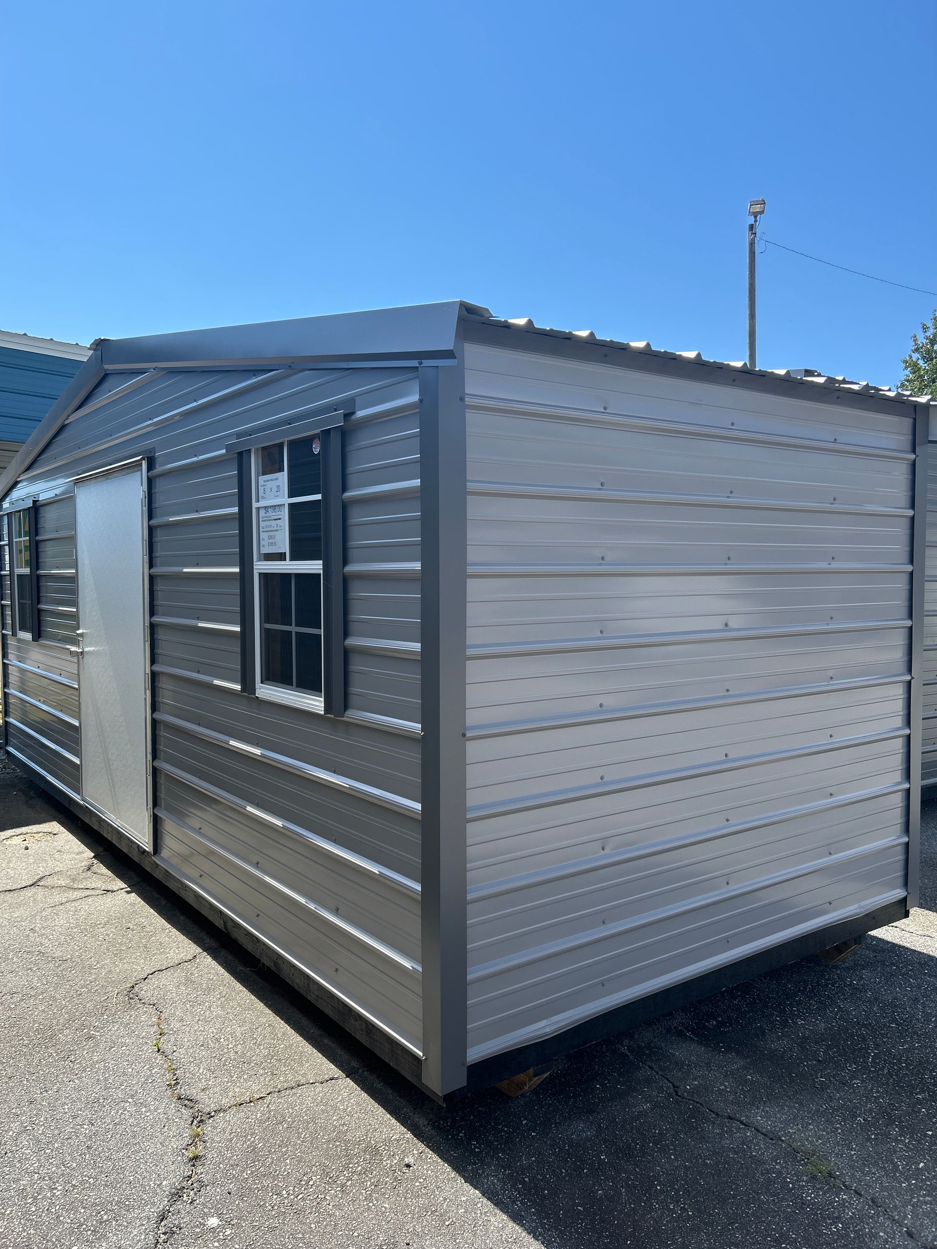 Gray metal shed with door and window on a sunny day.