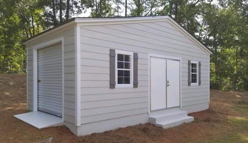 A white shed with a garage door and two windows